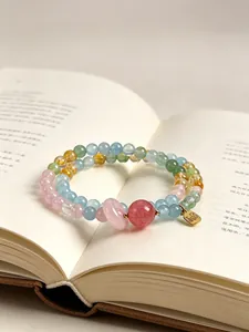 Vista de detalle de una pulsera de cuentas de cristal doble sobre un libro abierto.