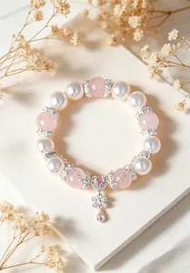 Primer plano de pulsera de cuarzo rosa y perlas con dijes de corazón y mariposa
