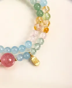 Detalle macro de pulsera de cuentas de cristal natural con dije de bendición dorado