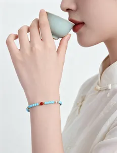 Primer plano de una pulsera de cuentas de turquesa de estilo neochino en la muñeca de mujer