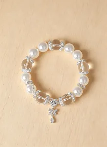 Detalle de una pulsera elegante de perlas y cristal blanco con un colgante de corazón