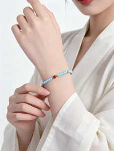 Detalle de pulsera de cuentas turquesas en la muñeca con elegante prenda de estilo chino