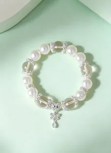 Vista detallada de una pulsera femenina de perlas y cristal con dijes de corazón y mariposa.