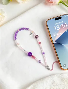 Detailed view of natural amethyst and rose quartz beaded phone charm on white fabric.