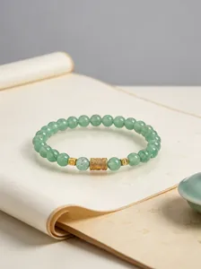 Nahaufnahme eines grünen Naturstein-Perlenarmbands mit einer goldenen Mantra-Perle