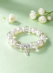 Primer plano de una elegante pulsera de perlas con cristal de corazón y mariposa