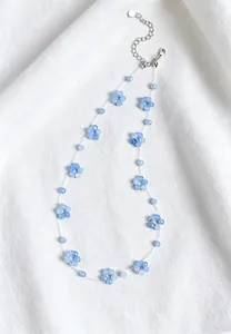 Close-up of blue beaded flower necklace with amazonite on white fabric background
