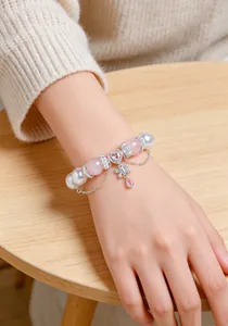 Primer plano de una pulsera de cuentas de cristal rosa y blanco con corazones en la muñeca