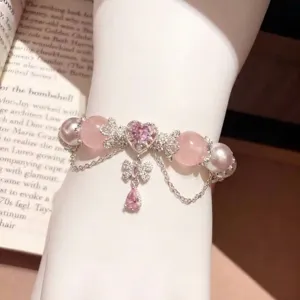 Elegante pulsera de cuentas de cristal rosa natural con dijes de corazón y mariposa en muñeca