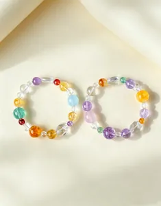 Detalle de dos pulseras de cuentas de cristal macaron de colores sobre un fondo crema suave