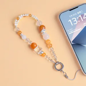 Close-up of a handmade beaded phone charm featuring natural crystals and shell elements