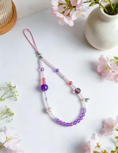 Detailed close-up of natural amethyst and rose quartz beaded phone charm with floral props.