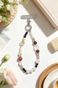 Detailed macro view of a premium beaded phone strap featuring white crystals and obsidian