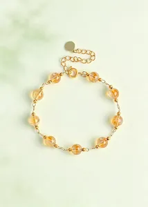 Vista detallada de una pulsera de cuentas de cristal amarillo natural con cadena de oro.