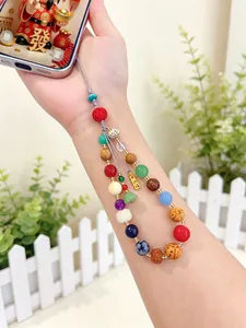 Hand holding a colorful multi-gemstone phone charm with diverse beads and a gold tag.