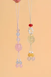 A detailed close-up showing two natural crystal nine-tailed fox beaded phone and bag charms