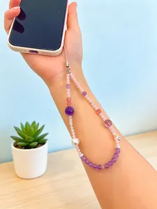Detail view of handmade amethyst and rose quartz beaded phone charm strap on arm