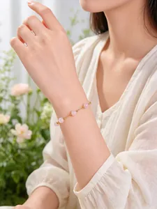 Elegante pulsera de cadena dorada con cuentas de cuarzo rosa en una modelo mujer.