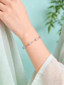 Detalle de una delicada pulsera de cuentas de cristal natural en la muñeca de una mujer