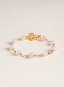 Vista macro detallada de una pulsera de cuentas de cuarzo rosa natural con detalles dorados