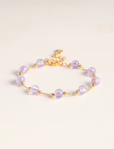 Detalle de una pulsera de cuentas de cristal lavanda con elegantes toques dorados
