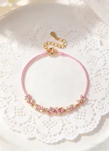 Detailed view of the pink cord bracelet featuring delicate pink and white crystal flowers.