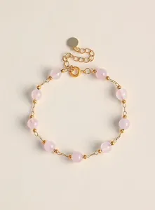Primer plano de una elegante pulsera de cadena dorada con cuentas de cristal rosa natural