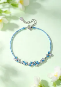 Detail view of a light blue braided rope bracelet with blue crystal floral accents