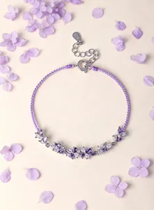 Detailed view of a purple braided cord bracelet with crystal flower accents and S925 silver tag.