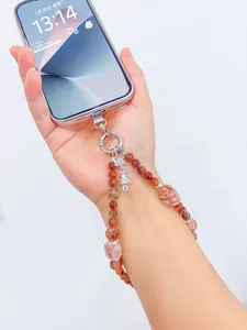 Hand holding iPhone with strawberry quartz beaded phone wrist strap charm