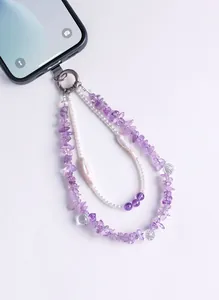 Close-up of amethyst and pearl beaded phone charm strap attached to a smartphone.