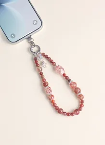 Detailed macro view of natural strawberry quartz beaded phone charm attached to a smartphone.