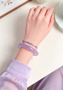 Detail view of elegant purple cat-eye stone bangle with floral crystal bracelet on wrist.
