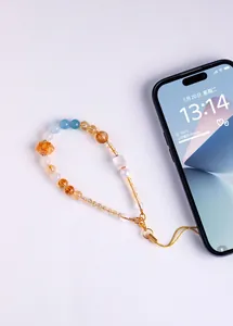 Detail view of handmade phone charm featuring natural pearls and yellow crystals.
