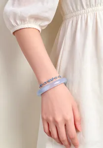 Close-up of cat eye stone bangle and blue crystal flower bracelet stacked on wrist