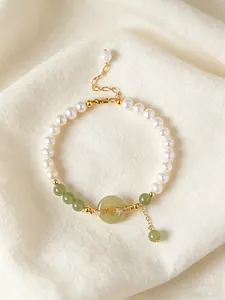 Close-up of pearl and green jade beaded bracelet with golden Ping'an Kou centerpiece