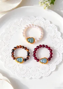 Detail view of natural pearl, tiger eye, and garnet beaded rings with jade gourd pendants.