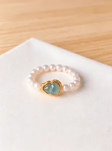 Detailed close-up of a pearl bead ring with a green jade gourd charm decoration