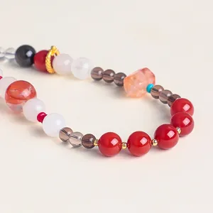 Close-up of elegant crystal and red agate beaded phone strap with gold spacer beads.