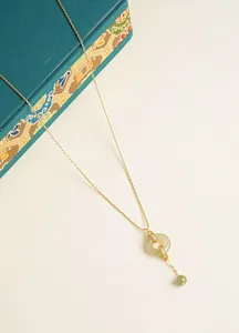 Close-up of elegant gold necklace with Hetian jade donut pendant and sparkling stones
