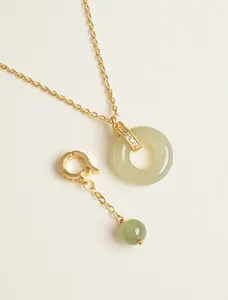 Detailed macro view of light green Hetian jade donut pendant with crystal-paved gold bail