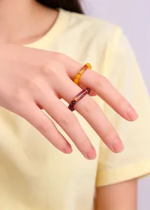 Close-up of natural garnet and agate beaded elastic rings on a hand for a vintage look.