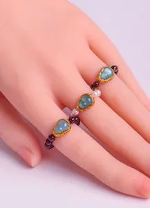Close-up detail of a beaded ring featuring green jade gourds, garnet beads and pearls