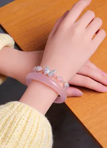 Detail view of natural pink crystal bead bracelet with silver butterfly charm on wrist