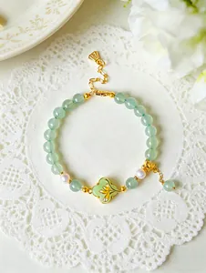 Detailed view of green aventurine and pearl bracelet with elegant enamel flower charm