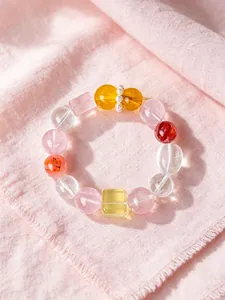 Detaillierte Nahaufnahme eines natürlichen bunten Kristallperlenarmbands auf rosa Stoff