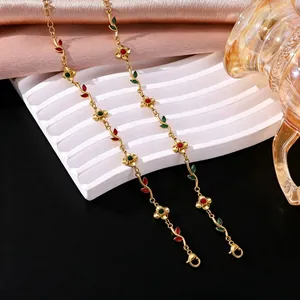 Detailed view of gold flower and leaf bracelet with red and green zircon stones