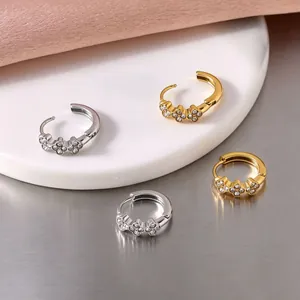 Close-up of gold and silver stainless steel hoop earrings with crystal flower details.