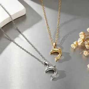 Vista detallada de collares con colgante de delfín en 3D dorado y plateado sobre metal
