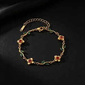 Detail of a gold-plated flower and leaf bracelet with red zircons and green enamel accents.